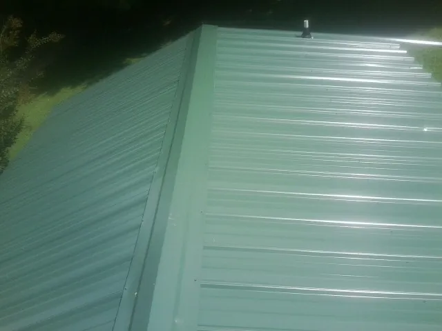 New green metal panels meeting at the ridge of a roof — Flat Roof Repair work by our crew in Lake Preston