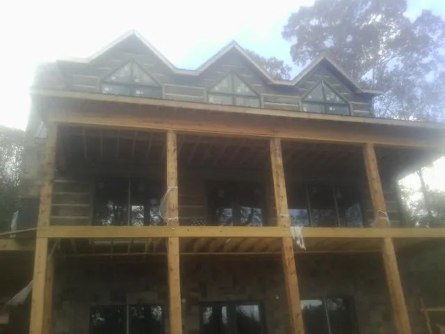 Dormers and porch framing on a large log home under construction — Roof Coating work by our crew in Lake Preston