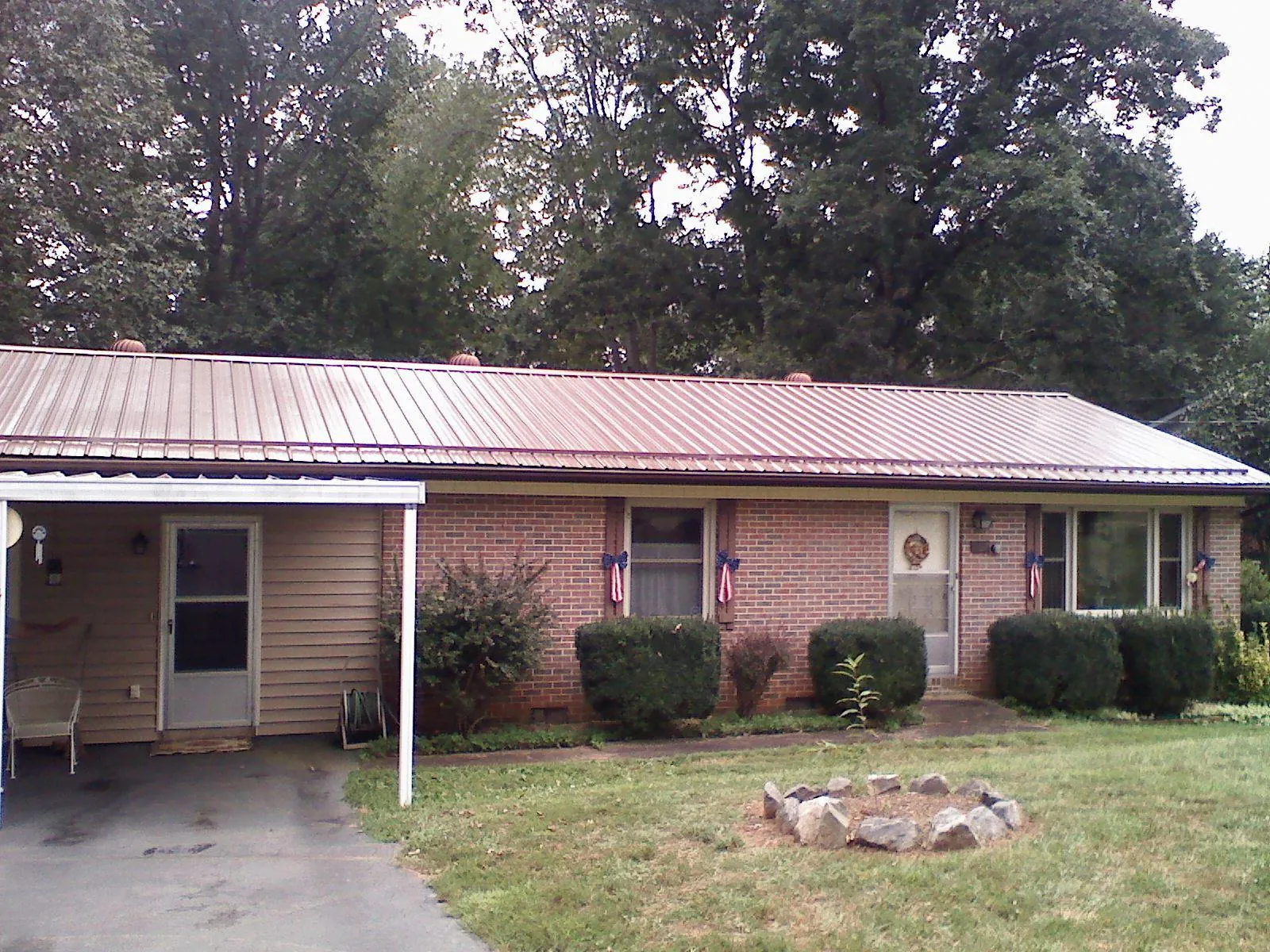 Bronze metal roof and carport on a brick ranch home — Roof Repair work by our crew in Lake Preston