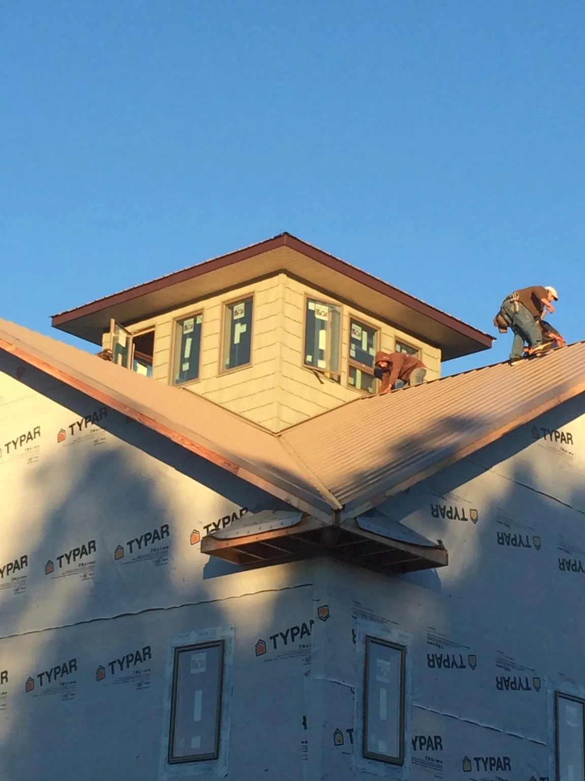 Roofers working around a rooftop cupola on a new metal roof at sunset — Roof Waterproofing in Lake Preston by Roofing Brothers